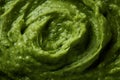 Pesto spread texture background. Green Italian homemade spilled sauce made of ground basil, garlic, pine seeds, olives and