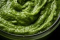 Pesto spread texture background. Green Italian homemade spilled sauce made of ground basil, garlic, pine seeds, olives and