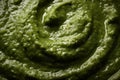 Pesto spread texture background. Green Italian homemade spilled sauce made of ground basil, garlic, pine seeds, olives and