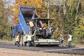 Heavy truck with body raise pours asphalt into an asphalt paver