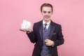 Pet care. Portrait of cheerful handsome man in elegant suit and with stylish hairdo standing holding cute bunny rabbit on his palm Royalty Free Stock Photo