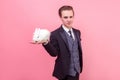 Pet care. Portrait of young handsome positive man in elegant suit holding rabbit on his palm. indoor studio shot isolated on pink Royalty Free Stock Photo