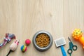 Pet care and training concept. Bowl with dry kibble food and accessories for dog and cat on wooden table. Flat lay, top view. Royalty Free Stock Photo