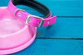 Pet collars and Bowls of pink on wooden background.