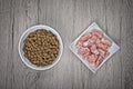 Pet food bowls of raw meat and kibble. Natural raw food versus kibble dried food.