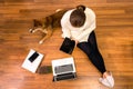 Pet Lover concept. Work from home and pets. Top view. Japanese dog and Young woman working with a laptop on the wooden floor. Royalty Free Stock Photo