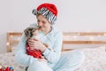 Pet owner celebrating Christmas New Year holiday alone. Young woman in Santa hat hugging cute miniature Australian shepherd puppy Royalty Free Stock Photo