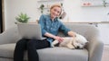 Pet owner with laptop fondling dog on kitchen couch
