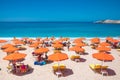 PETANI beach, Greece - July 21, 2020: People relaxing, yellow sunbeds, orange umbrellas, white sand, azure water.