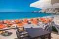 PETANI beach, Greece - July 21, 2020: People relaxing, yellow sunbeds, orange umbrellas, white sand, azure water.