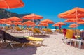 PETANI beach, Greece - July 21, 2020: Yellow sunbeds, orange umbrellas, white sand, azure water of Petani beach.