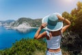 Petani beach Kefalonia. Young woman holding blue sun hat enjoying beautiful panorama of blue bay lagoon surrounded by