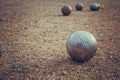 Petanque balls on a sandy pitch with other metal ball