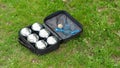 Petanque set with six metal balls in a black case on green grass. Royalty Free Stock Photo