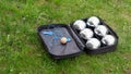 Petanque set with six metal balls in a black case on green grass. Royalty Free Stock Photo