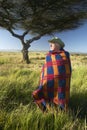 Peter Bender in Senior Elder robe of Masai standing near Acacia Tree in the Lewa Conservancy of Kenya Africa