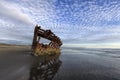 Peter Iredale shipwreck under a partly cloudy sky.