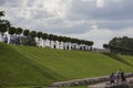 Row of manicured Tilia trees in line on and people walking on green grass lawn hill of Garden of Venus with blue sky