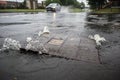 Flood water from rain spouting up through manhole cover on a street road Royalty Free Stock Photo