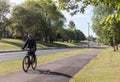 Cyclist riding along a cycle path beside a road through an urban area with trees