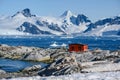 Petermann Island, beautiful Antarctic Island with penguins on rocks, abandoned station and snow covered mountains behind Ocean. Royalty Free Stock Photo