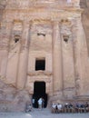 Vertical view of tourists next to the door of a tomb in the mountain of Petra, Jordan