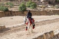 Bedouin riding a horse in Petra archaeological park at cold winter day