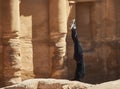 Young girl in a black sports suit is training a handstand in front of the ancient monastery Al-Deir. The moment stands in Petra,