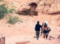 Petra, Jordan - 7th october, 2022: bedouin master with donkey take overweight Petra female visitor client down stairs from little