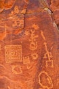 Native American petroglyphs etched into a red walk wall.