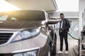 Petrol station, auto fueling concept. Portrait of young handsome African man standing outdoors at gas station and