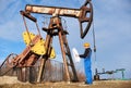 Petroleum engineer controlling work of oil well pump jack. Royalty Free Stock Photo