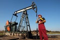 Petroleum Engineer Talking to Smartphone in Front of Oil Pump