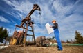 Oil man controlling work of pump jack. Royalty Free Stock Photo