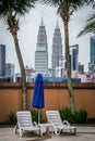 Petronas Towers of Kuala Lumpur in the city skyline behind a pair of sun tan deck chairs