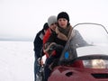 Petrozavodsk / Russia - March 1, 2019: People ride a snowmobile on a frozen, icy lake. A woman drives a snowmobile with difficulty Royalty Free Stock Photo