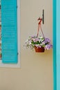Petunias in flower pot hanging on decorative bracket near window shutter Royalty Free Stock Photo