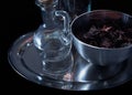 Pewter plate with a half-filled glass carafe and a bowl of dried herbs in a deliberately dark environment