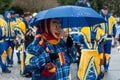 Portrait of masked person with blue umbrella parading in the street