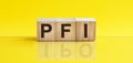 Pfi word is made of wooden building blocks lying on the yellow table