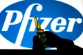 Pfizer coronavirus vaccine pharmaceutical corporation. Logo and hand with vaccine