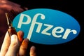 Pfizer coronavirus vaccine pharmaceutical corporation. Logo and hand with vaccine