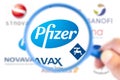 Pfizer logotype enlarged with a magnifying glass with other logotype laboratories on blurry background