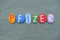 Pfizer, company logo composed with multi colored stone letters over green sand