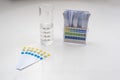 ph control strips, graduated cylinder with water and box of strips with color patterns