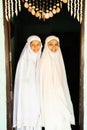 Portrait of two charming Muslim teenage girls in traditional clothing smiling at camera