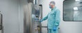 Pharmaceutical factory man worker in protective clothing working with control panel in sterile working conditions Royalty Free Stock Photo