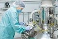 Pharmaceutical factory woman worker in protective clothing operating production line in sterile environment Royalty Free Stock Photo