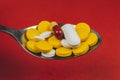 Pharmaceutical medicine pills, on spoon against red background Royalty Free Stock Photo