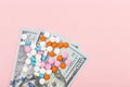 Pharmaceutical medicine pills, tablets and syringe on US dollars euros on pink background. Healthcare concept. Crisis